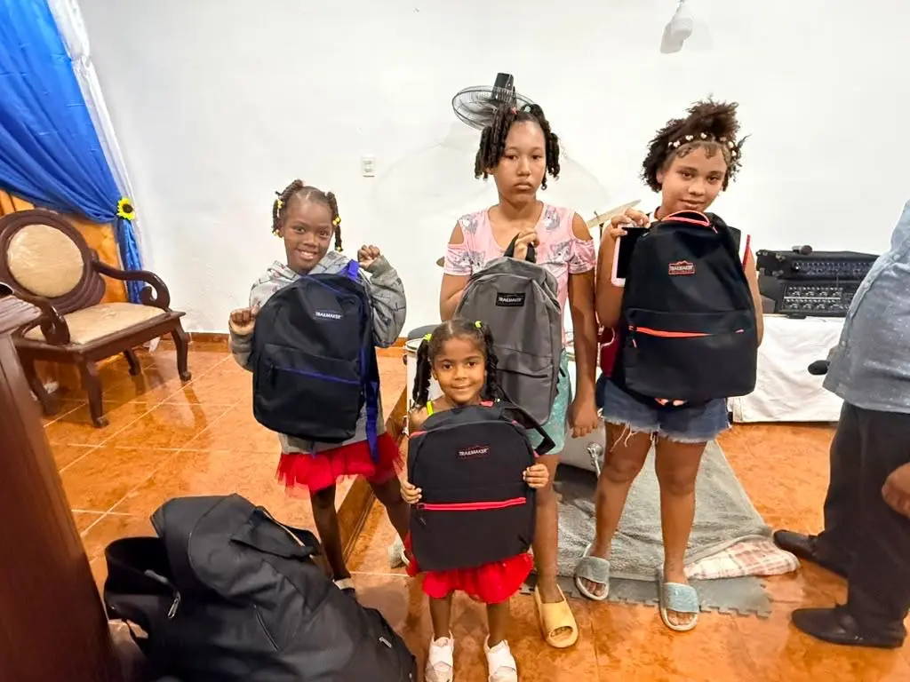 Girls holding backpacks received during the drive