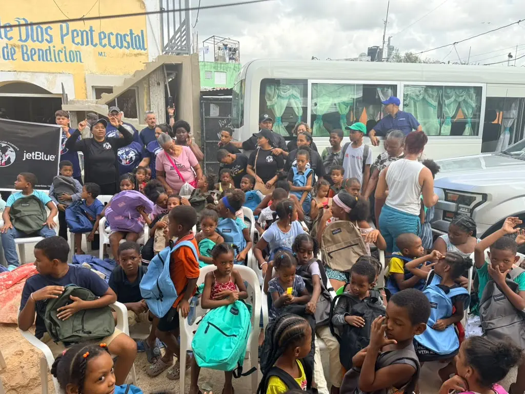 Children displaying their backpacks with community volunteers