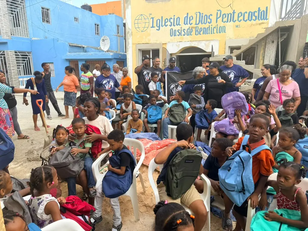 Community members helping children receive new backpacks