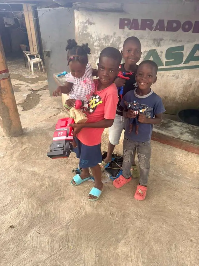 Children proudly holding toys received during a community giveaway